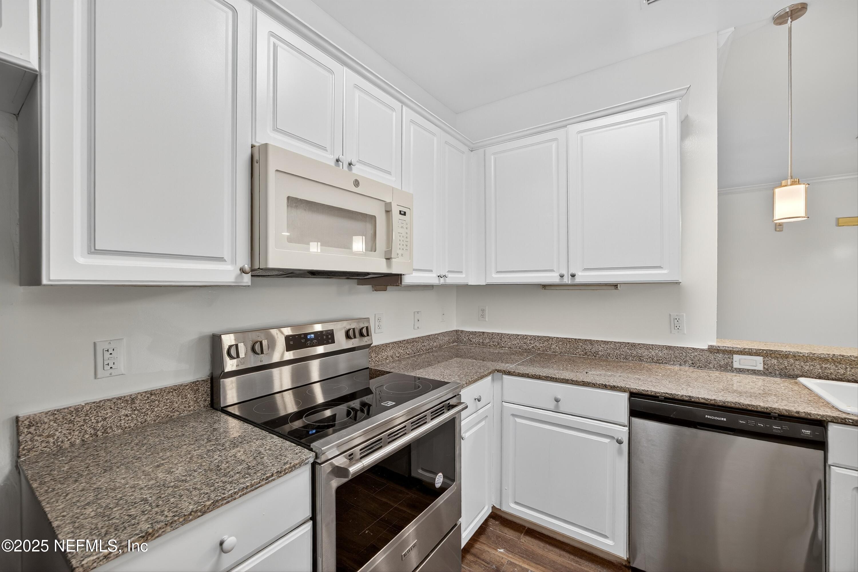 210 Presidents Cup Way, Unit 101 St. Augustine, FL 32092 - Photo 18 of 37 a kitchen with granite countertop white cabinets and stainless steel appliances