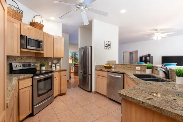 a kitchen with stainless steel appliances granite countertop a sink and dishwasher a refrigerator with wooden cabinets