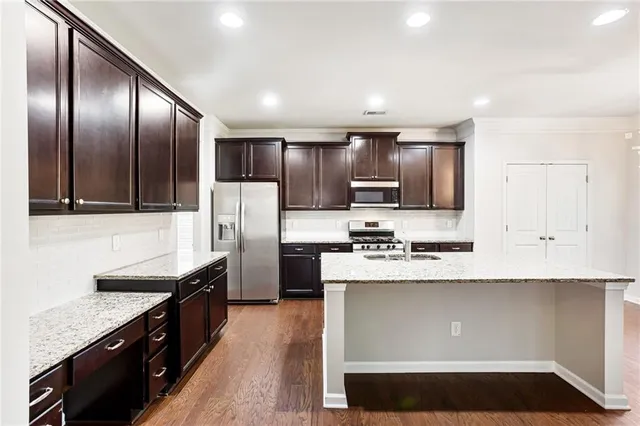 a large kitchen with stainless steel appliances granite countertop a stove a sink and a refrigerator