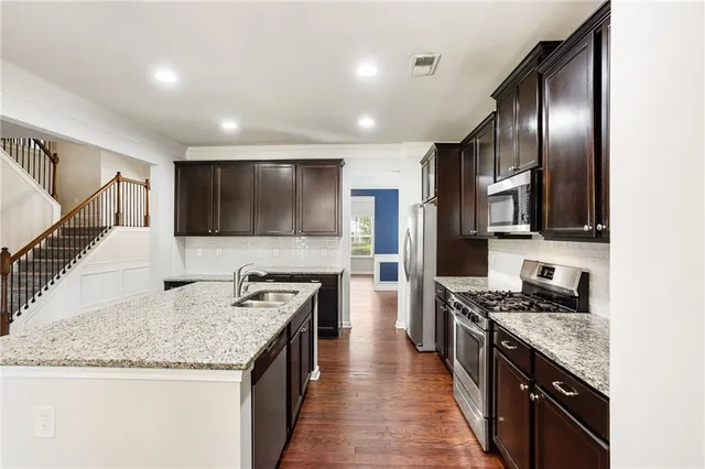 a kitchen with stainless steel appliances granite countertop a sink stove and refrigerator