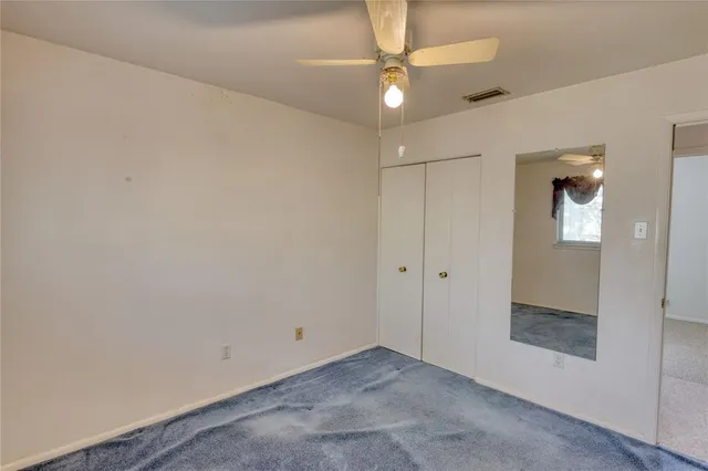 a view of an empty room with closet and a chandelier fan