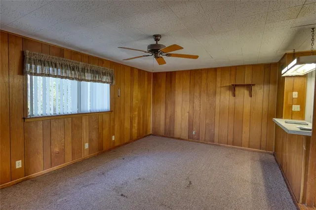 an empty room with chandelier fan and windows