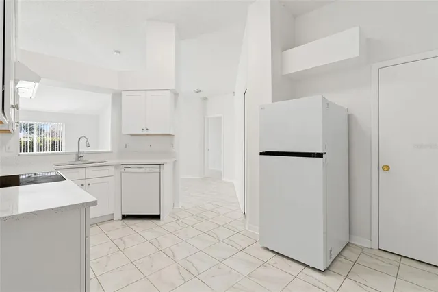 a kitchen with white cabinets and refrigerator