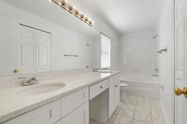 a bathroom with a sink double vanity granite tub shower and a mirror