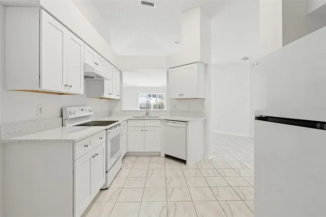 a kitchen with white cabinets and white appliances