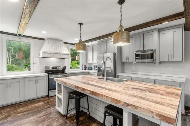 a kitchen with stainless steel appliances granite countertop a sink a stove a refrigerator cabinets and chairs