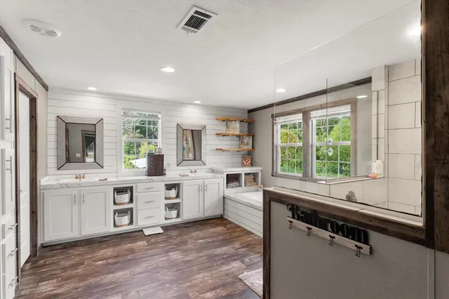 a large white kitchen with a stove a sink dishwasher a dining table and chair with wooden floor