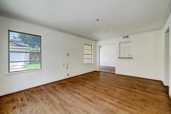 a view of empty room with wooden floor and fan