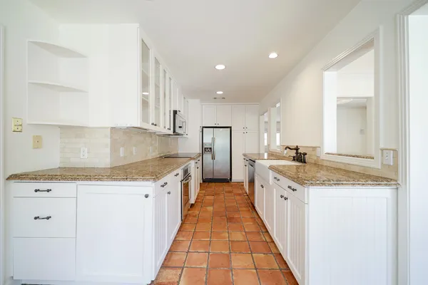 a large kitchen with granite countertop a sink and cabinets
