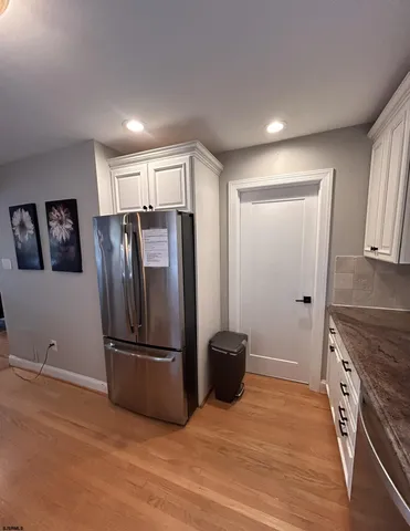 a view of a kitchen with refrigerator and wooden floor