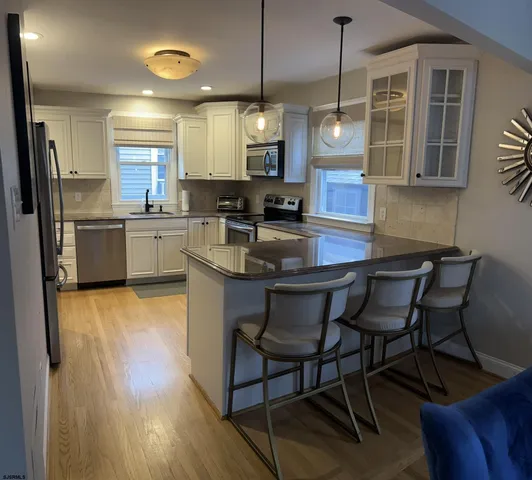 a kitchen with stainless steel appliances granite countertop a kitchen island hardwood floor sink stove dining table and chairs