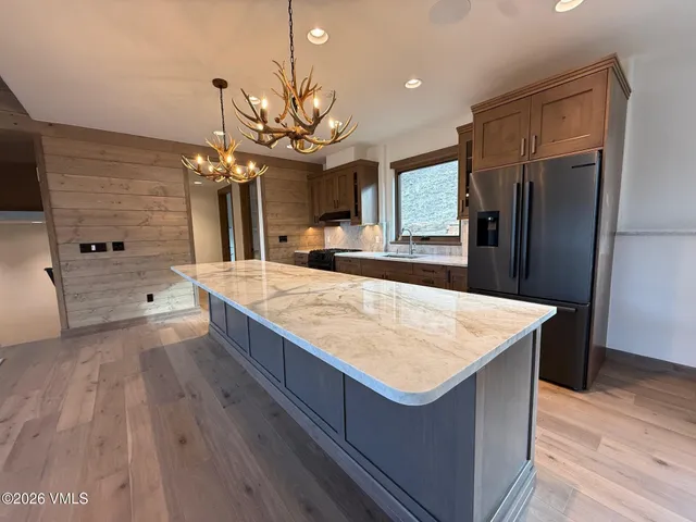 a large kitchen with kitchen island a stove a sink a refrigerator and a wooden floor