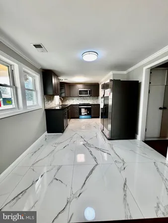 a large white kitchen with kitchen island a refrigerator stove a sink dishwasher and wooden cabinets