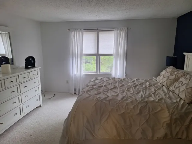 a bedroom with a bed and a flat tv screen on the dresser