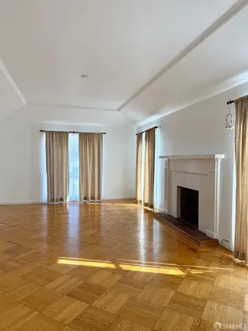 a view of empty room with wooden floor and fireplace