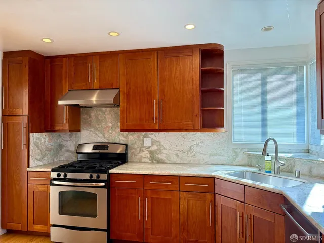 a kitchen with stainless steel appliances granite countertop a stove a sink and a microwave
