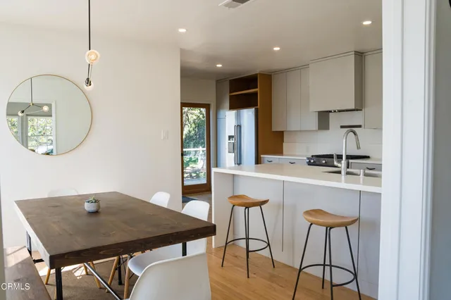 a kitchen with stainless steel appliances granite countertop a stove a refrigerator a microwave a sink a dining table and chairs with wooden floor