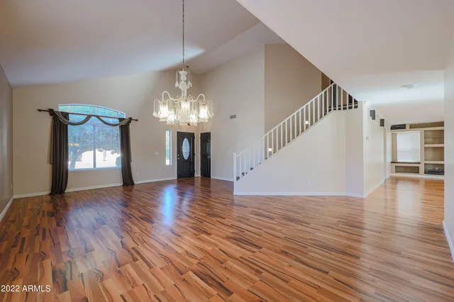 a view of an empty room with wooden floor and stairs