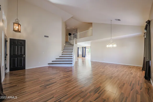 a view of an empty room with wooden floor and stairs