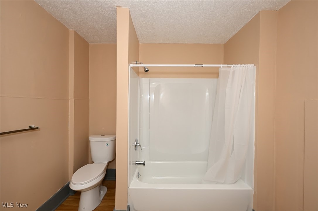 667 Elma Street Akron, OH 44310 - Photo 42 of 42 Full bathroom with shower / bathtub combination with curtain, a textured ceiling, and wood finished floors