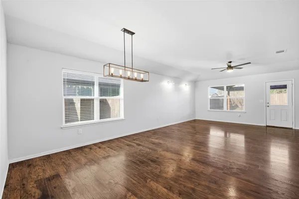 a view of an empty room with a window and wooden floor
