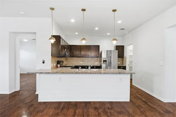 a large kitchen with granite countertop a sink a counter top space and stainless steel appliances