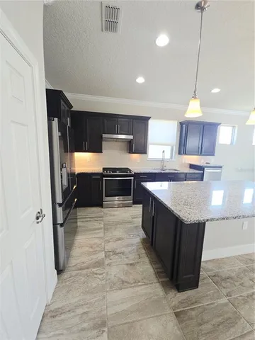 a kitchen with stainless steel appliances granite countertop a stove a sink dishwasher a refrigerator and a oven with wooden cabinets