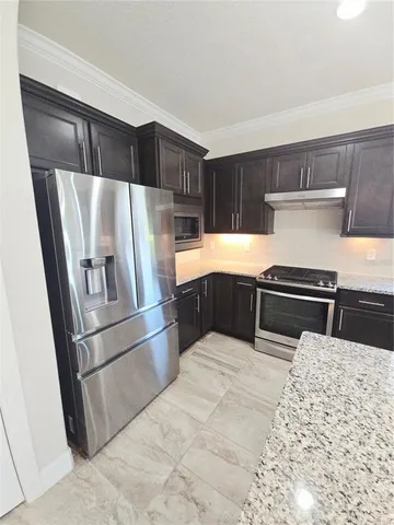 a kitchen with granite countertop a refrigerator and a stove top oven