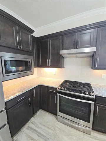 a kitchen with granite countertop a stove and a microwave