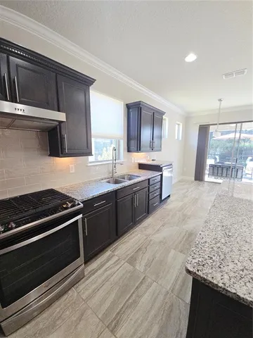 a kitchen with stainless steel appliances granite countertop a stove a sink and a microwave