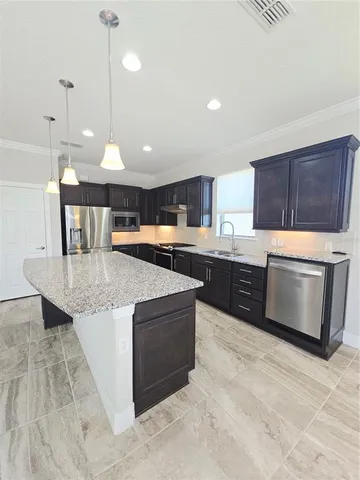 a kitchen with stainless steel appliances granite countertop a stove a sink dishwasher a refrigerator and a oven with wooden floor