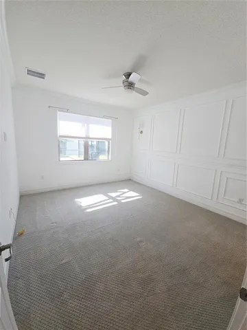 an empty room with windows and fan