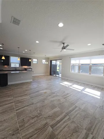 a view of an empty room with kitchen and window