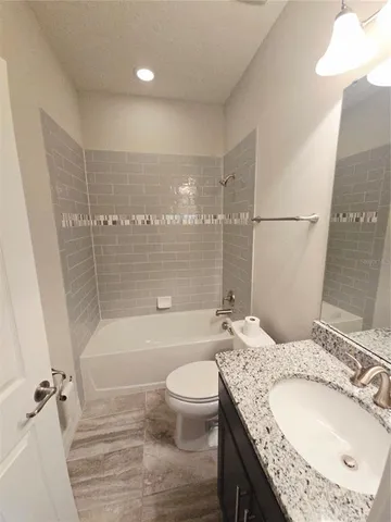 a bathroom with a granite countertop sink a toilet and shower