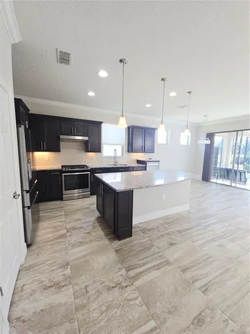 a large kitchen with stainless steel appliances kitchen island granite countertop a table and a sink