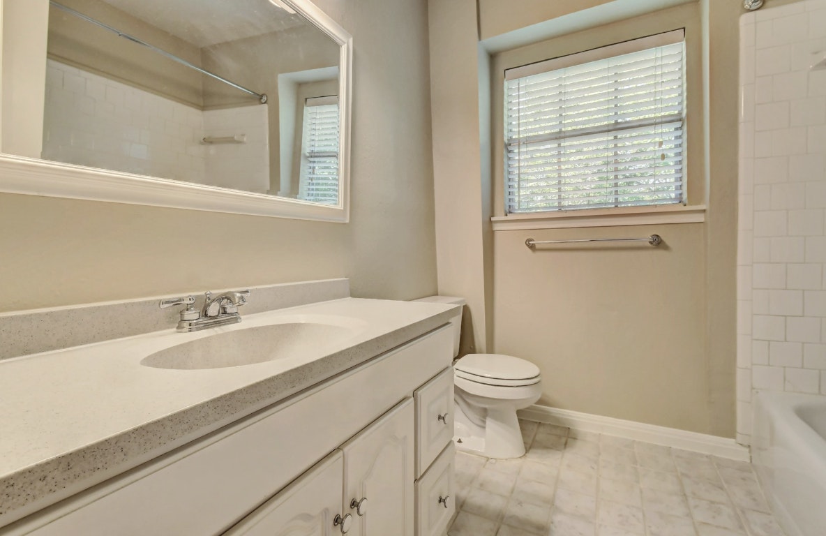 1704 East M. Franklin Avenue, Unit B Austin, TX 78721 - Photo 16 of 26 a bathroom with a granite countertop sink a toilet and a window