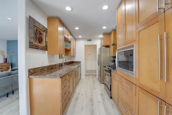 a kitchen with stainless steel appliances granite countertop a refrigerator a stove and a sink