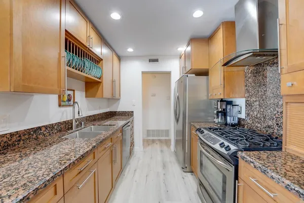 a kitchen with granite countertop a sink stove and refrigerator