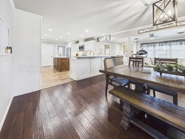 a open kitchen with stainless steel appliances granite countertop a stove a sink a refrigerator and white cabinets with wooden floor