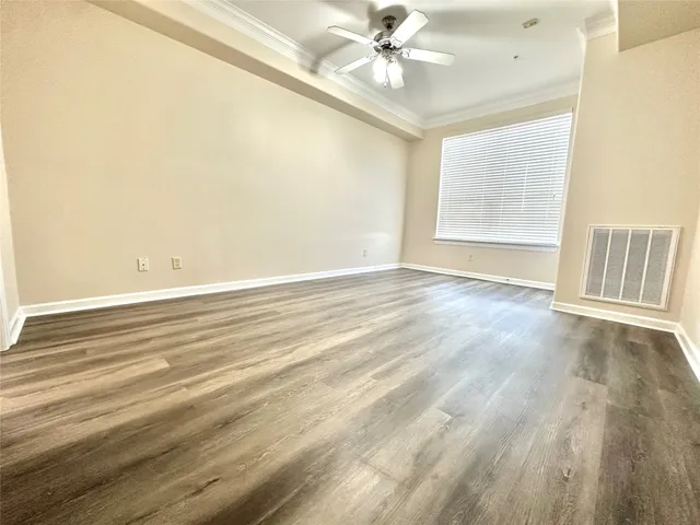 an empty room with wooden floor fan and windows