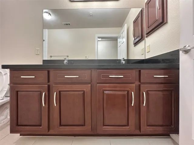 a bathroom with a granite countertop sink and a mirror