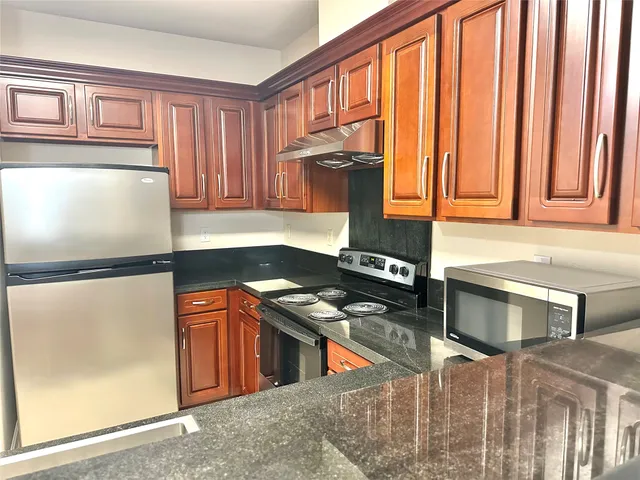a kitchen with stainless steel appliances granite countertop a refrigerator and a stove top oven