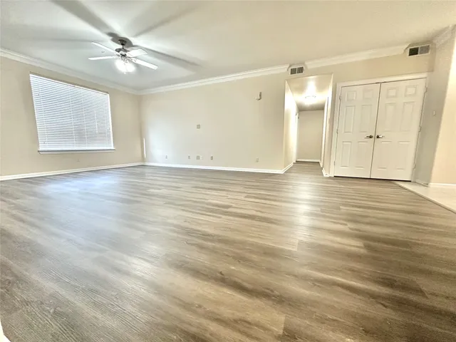 an empty room with wooden floor ceiling fan and windows