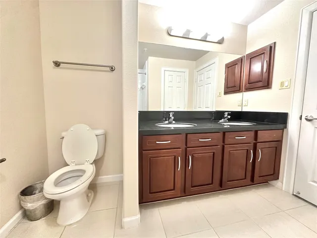 a bathroom with a granite countertop toilet sink and mirror