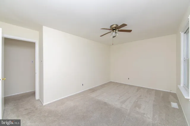 an empty room with a ceiling fan and a window