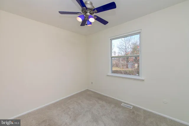 an empty room with a window and a fan