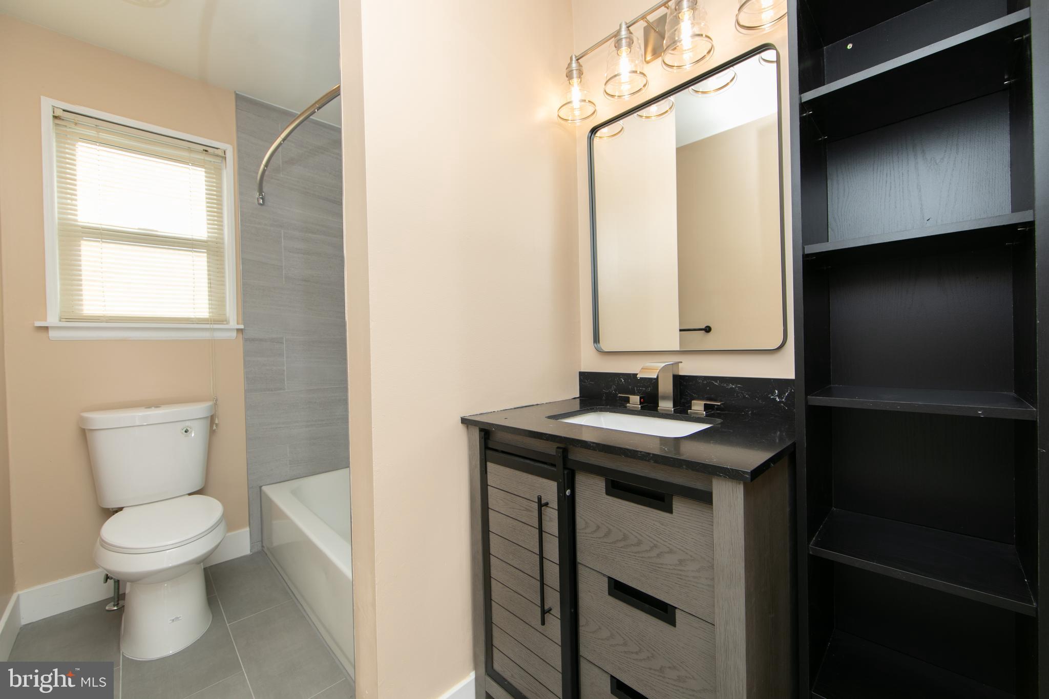 1042 Central Avenue Runnemede, NJ 08078 - Photo 26 of 36 a bathroom with a granite countertop toilet a sink and a mirror
