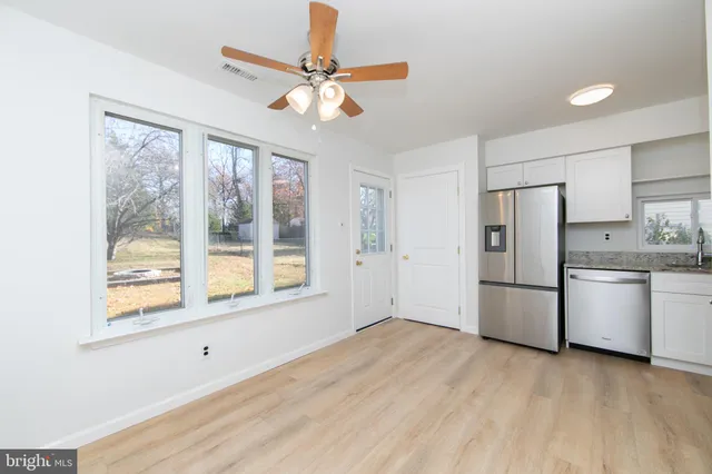 a view of a kitchen with a stove cabinets a ceiling fan and wooden floor