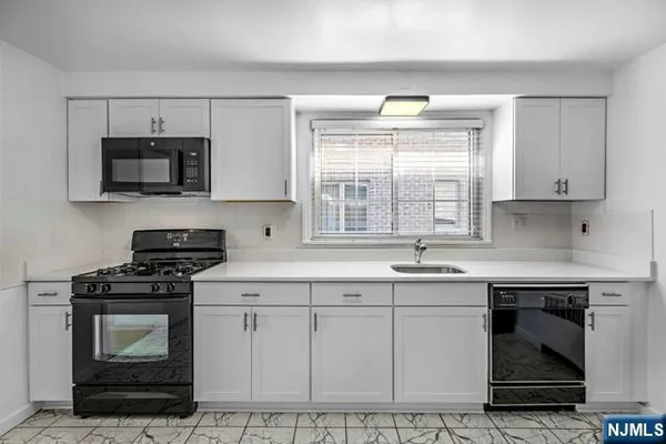 a kitchen with cabinets stainless steel appliances a sink and a window