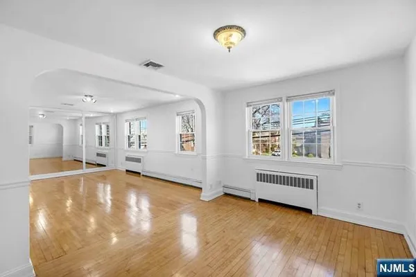 a view of an empty room with a window and wooden floor